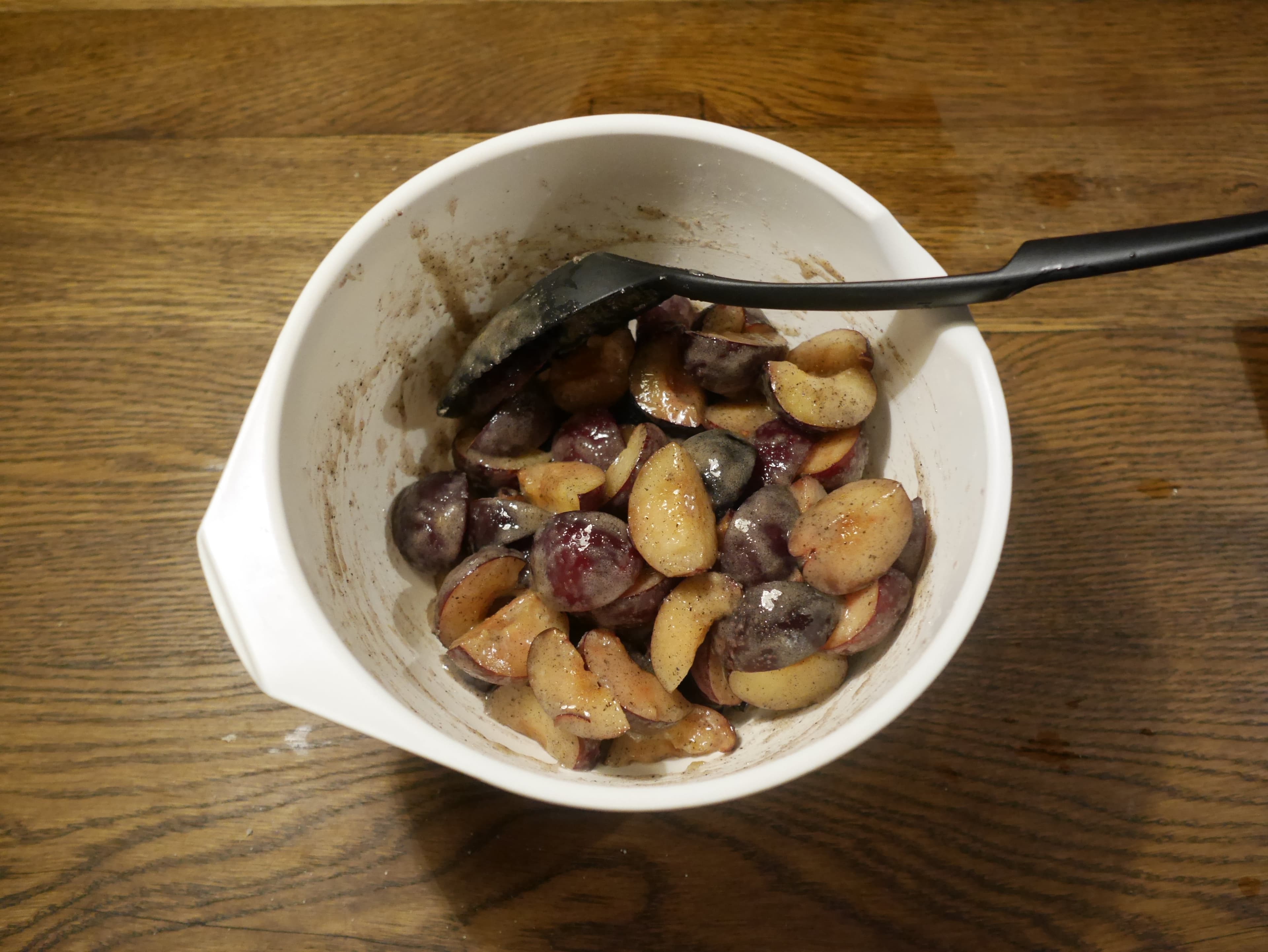 Plums, sugar, cornstarch and vanilla mixed together in a bowl.