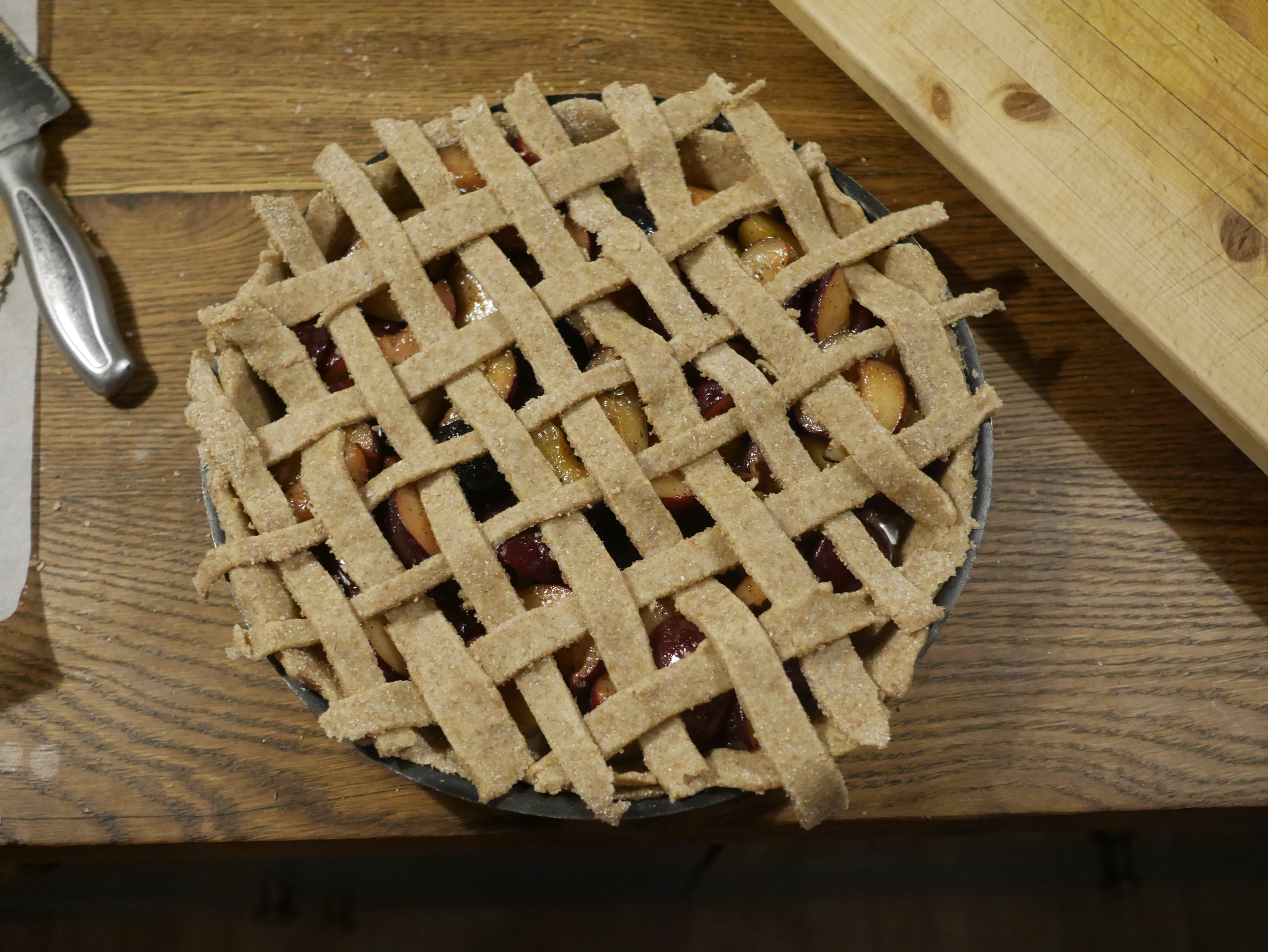 A plum pie with an uncooked dough lattice on top.